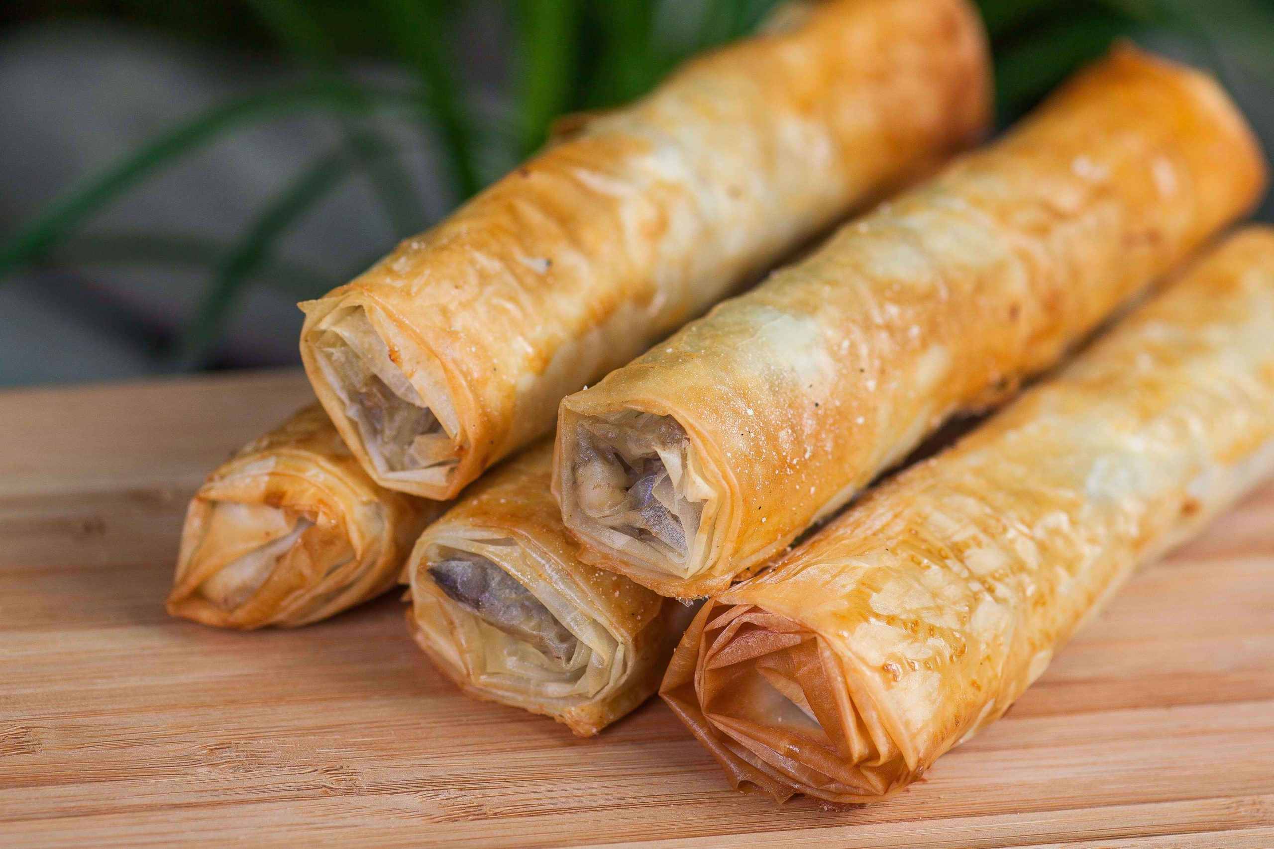 Baked roll of filo dough, with a filling, on a wooden board