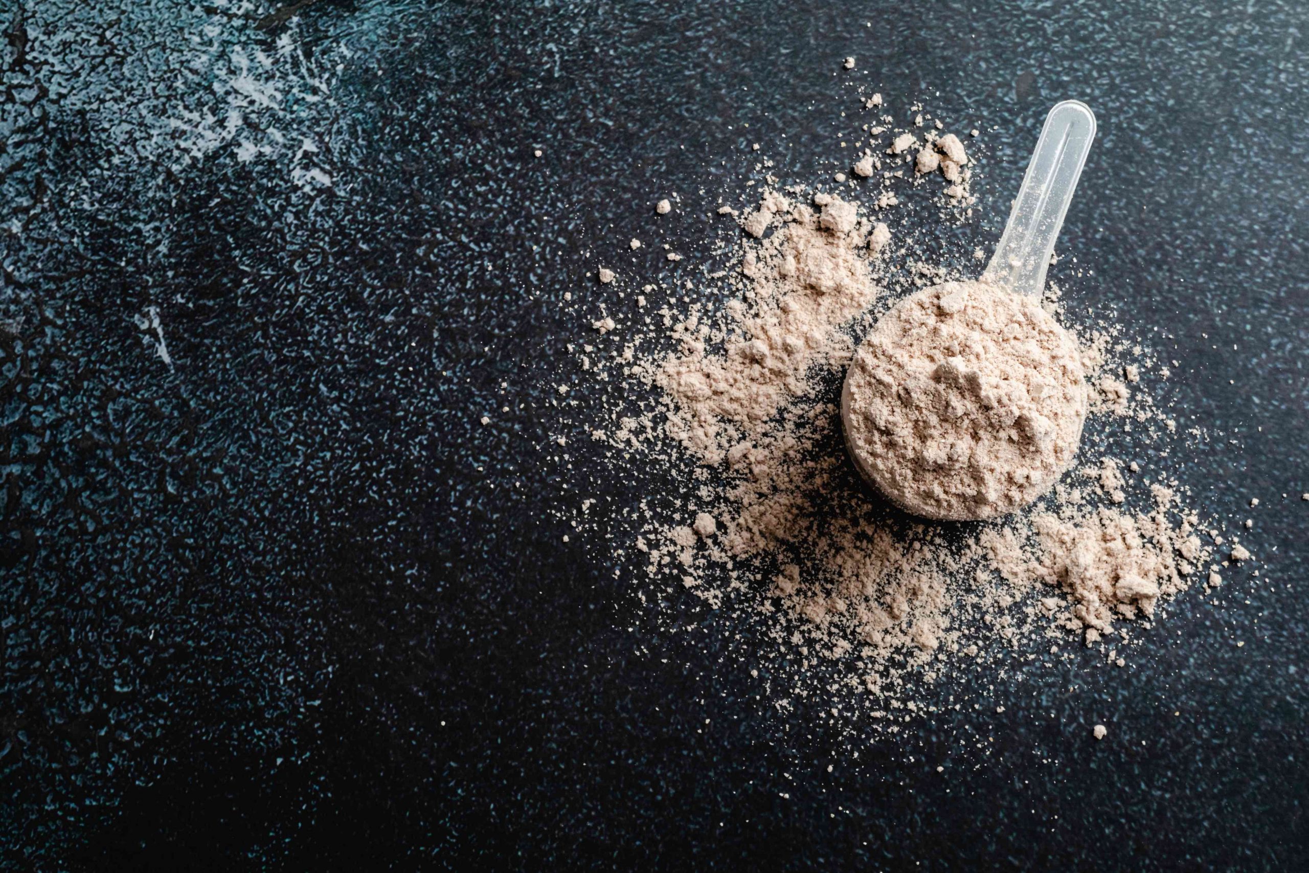 Top view whey protein scoop on dark background, copy space
